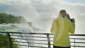 A woman looks at Niagara Falls through a coin operated binoculars. Tourism in the USA concept