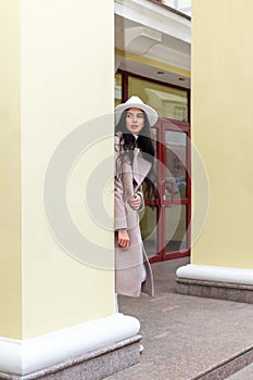 woman looks out from behind a column