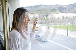 Woman looks out the window at the street.