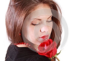 Woman looks at red rose on her shoulder