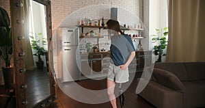 Woman looks at reflection in mirror recognizing uniqueness