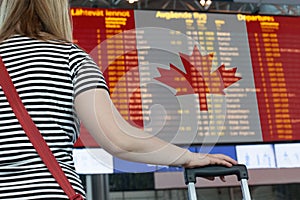 Woman looks at the scoreboard at the airport. Select a country Canada for travel or migration