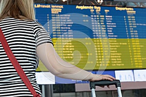 Woman looks at the scoreboard at the airport. Select a country Ukraine for travel or migration