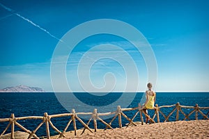 Woman looks at the sea and the island of Tiran