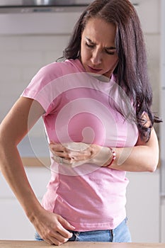 Woman looks at sweat stains visible from on her pink shirt