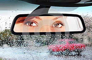 Woman looks to rear-view mirror