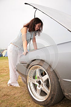 Woman looks under a car cowl