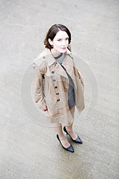 Woman at loose beige coat on greyish square