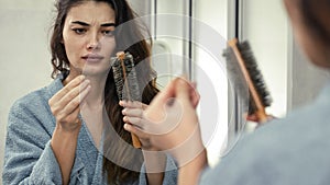 Woman losing hair on hairbrush in hand