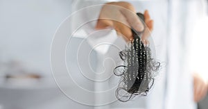 Woman losing hair on hairbrush in hand, soft focus