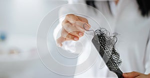 Woman losing hair on hairbrush in hand, soft focus