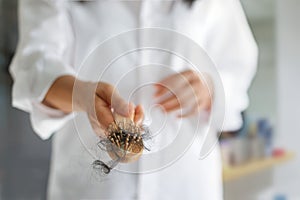 Woman losing hair on hairbrush in hand, soft focus