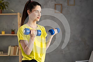 woman losing weight at home and exercising with dumbbells. Beautiful latin girl in sportswear with dumbbells in her