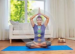 Woman in lotus pose doing yoga with seven chakras