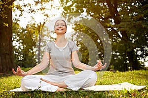 Woman in lotus pose meditate in green park