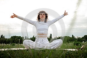 Woman lotus pose retreat in park. Young girl hobby doing meditation. Sportswoman raised arms up sitting yoga mat and