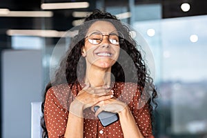 A woman in love is working in the office at work, a Latin American businesswoman in glasses is holding the phone to her