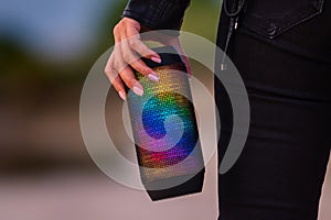 Woman loves to listen music with portable LED multicolour wireless bluetooth speakers. Enjoying the music outdoors.