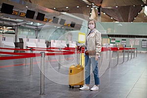 Woman with luggage stands at almost empty check-in counters at the airport terminal due to coronavirus pandemic/Covid-19 outbreak