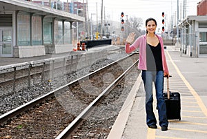 Woman with luggage waving at train station
