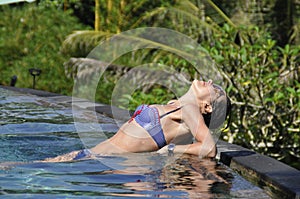 Woman in luxury spa swimming pool in the middle of the tropical forrest