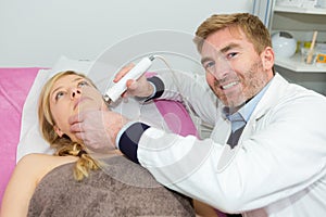 woman lying at beauticians during laser therapy photo