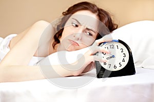 Woman lying a bed with alarm (focus on alarm)