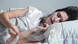 Woman lying in bed and Blowing Her Nose