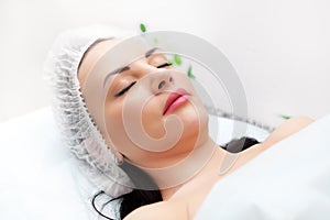 Woman lying on bed while getting beauty injection in neck. Facial treatments. Beauty concept. photo