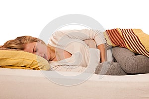 Woman lying in bed holding belly because of the pain in stomac.