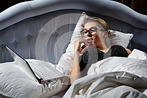 Woman lying on bed with a laptop