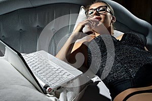 Woman lying on bed with a laptop