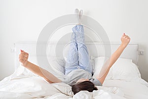 Woman lying in bed with legs raised up against a wall