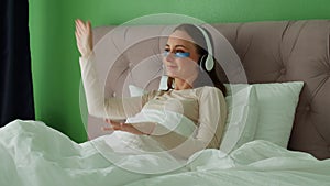 Woman lying in bed listening to music, audiobook, podcast, enjoying meditation for sleep and peace of mind in wireless