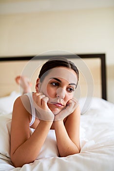 Woman lying in bed looking downcast.