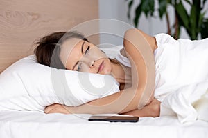 Woman lying on bed looking at phone waiting for call