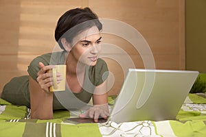 Woman lying on bed using laptop