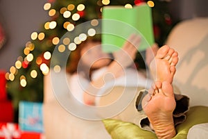 Woman lying on the couch barefoot reading