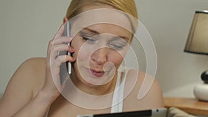 Woman lying on the couch with a computer tablet and talking on the phone