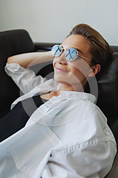 A woman lying on the couch with her glasses on and wriggling
