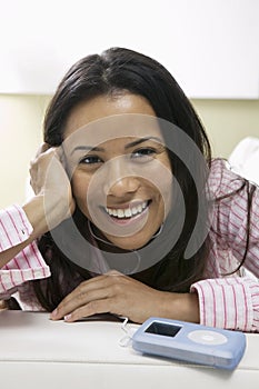 Woman lying on couch Listening to Music on MP3 Player portrait