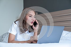 Woman lying down the bed with laptop and phone