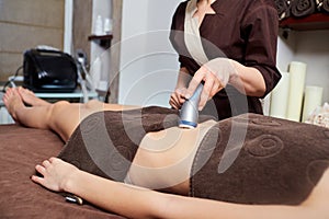 A woman lying down doing cryolipolysis treatment.