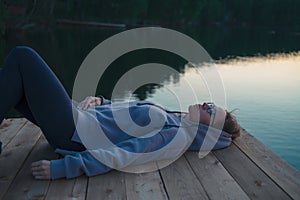 Woman lying down on the pier at lake