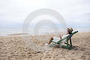 A woman lying down and reading book on the beach chair with feeling relaxed