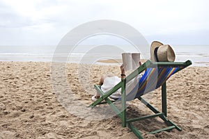 Woman lying down and reading book on the beach chair with feeling relaxed