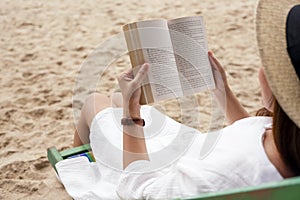A woman lying down and reading book on the beach chair with feeling relaxed