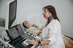 Woman is lying down and undergoing ultrasonic test of the thyroid gland