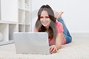 Woman lying on floor in front of laptop