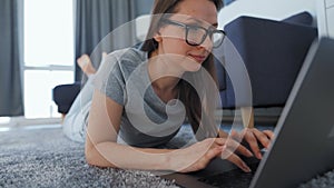 Woman is lying on the floor and and makes an online purchase using a credit card and laptop. Online shopping, lifestyle